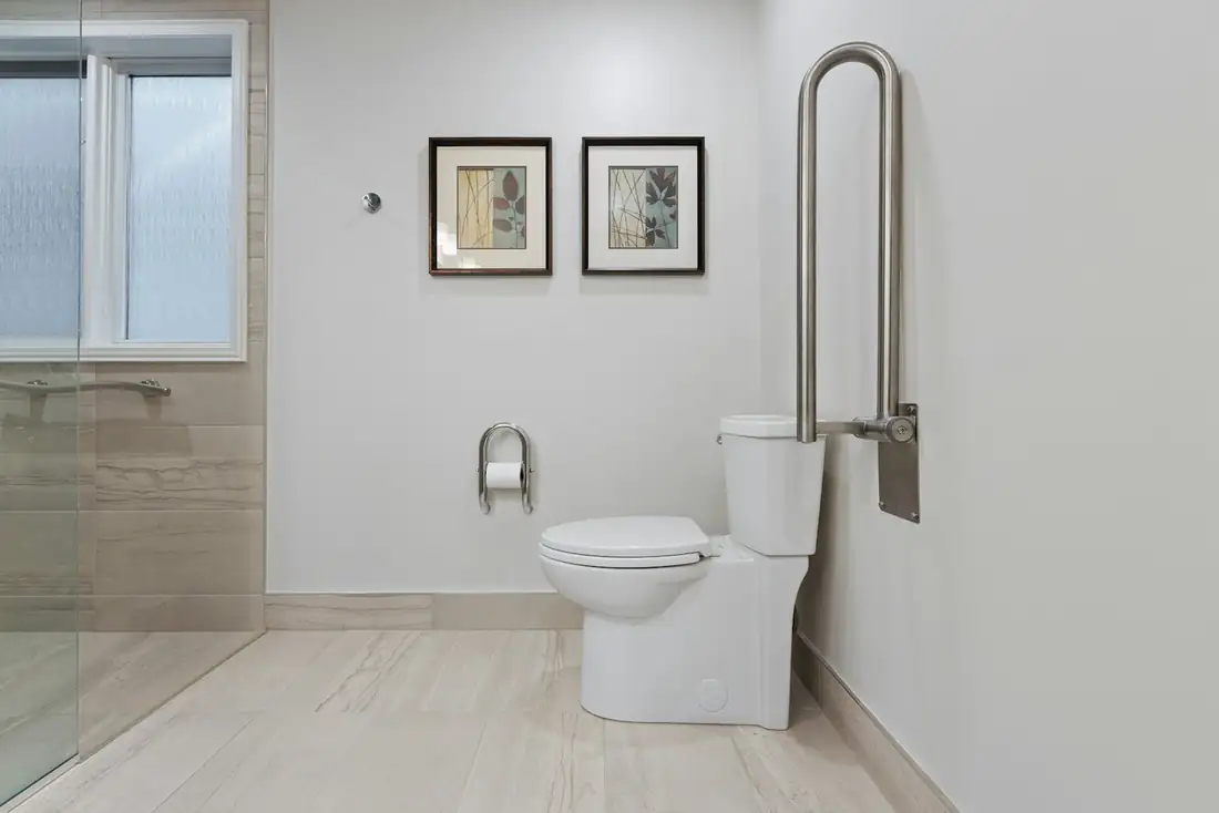 Salle de bain claire avec barre d’appui relevable à côté des toilettes
