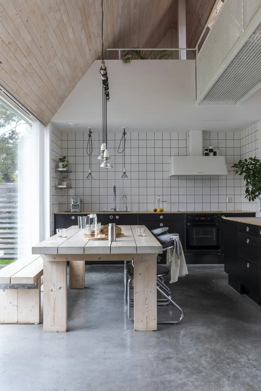 Cuisine sous un plafond en pente lambrissé, faïence blanche, table en bois massif