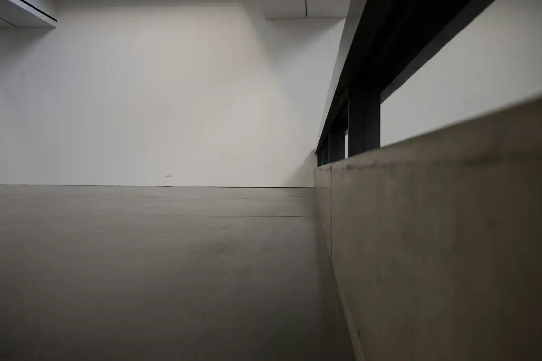 Pièce vide au sol lissé, mur blanc et lumière rasante